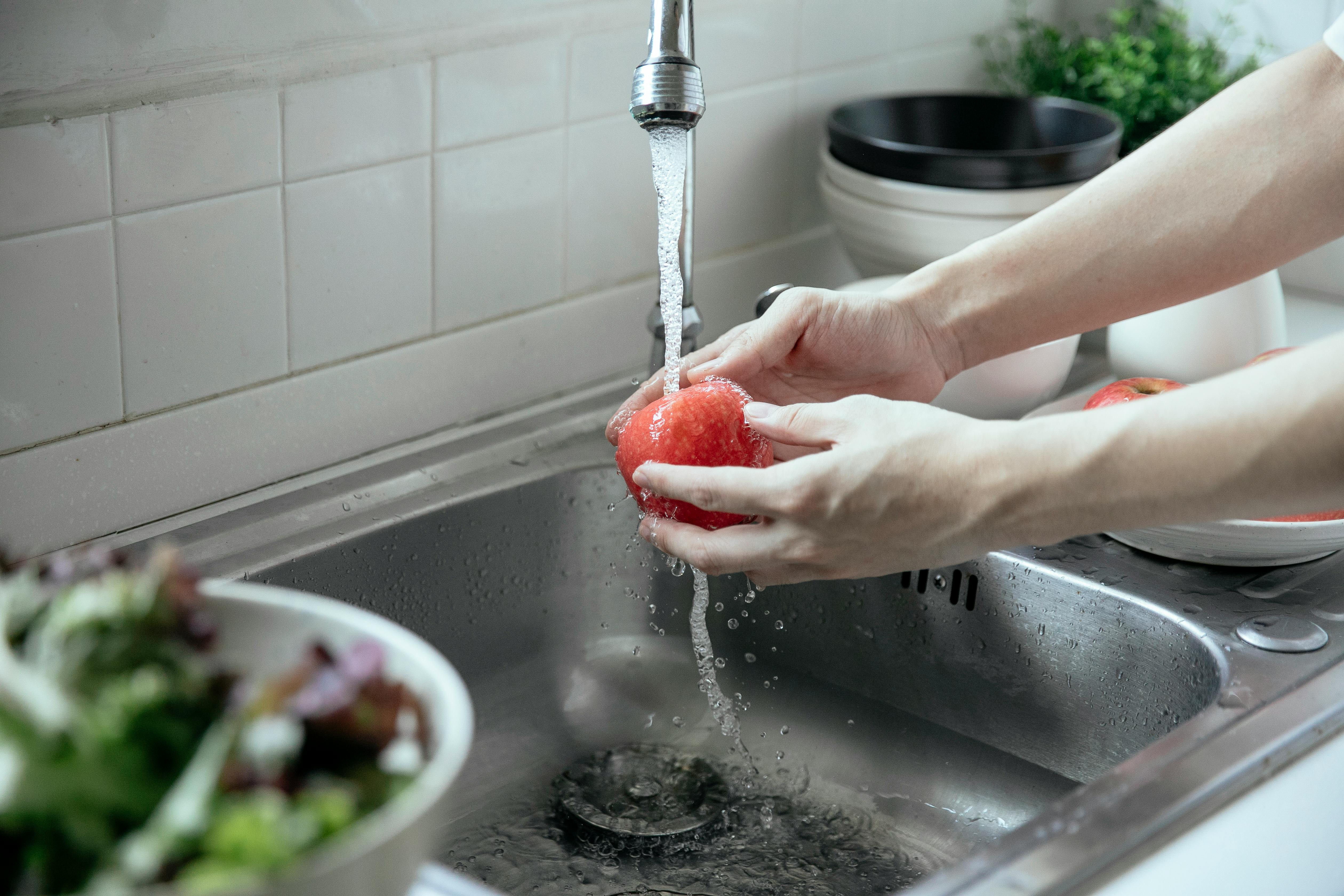 Person washing a tomato